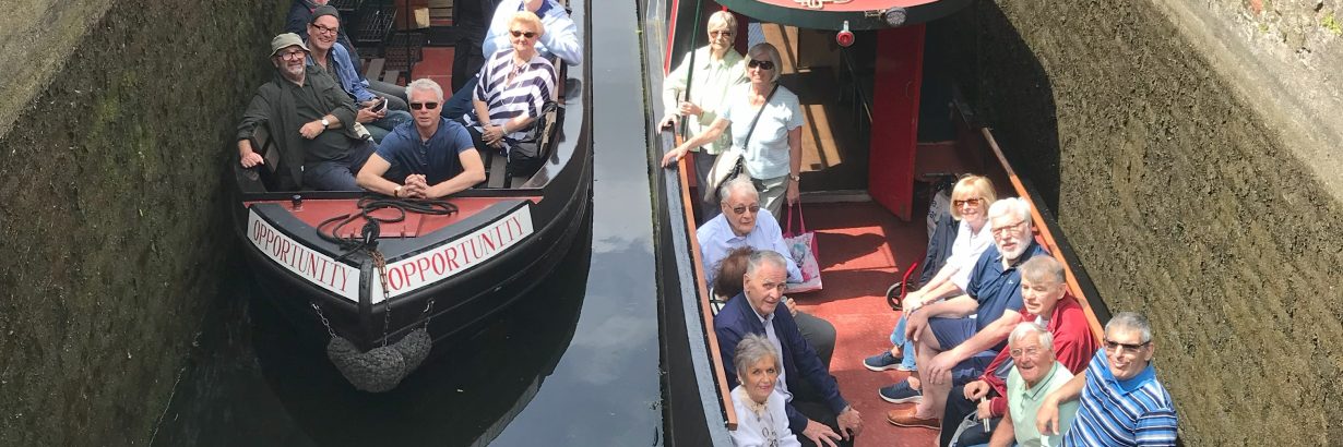 Two red canal boats with passengers sat in the front.