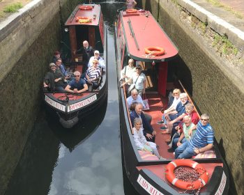 Two red canal boats with passengers sat in the front.