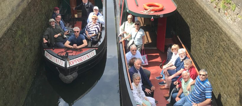 Two red canal boats with passengers sat in the front.