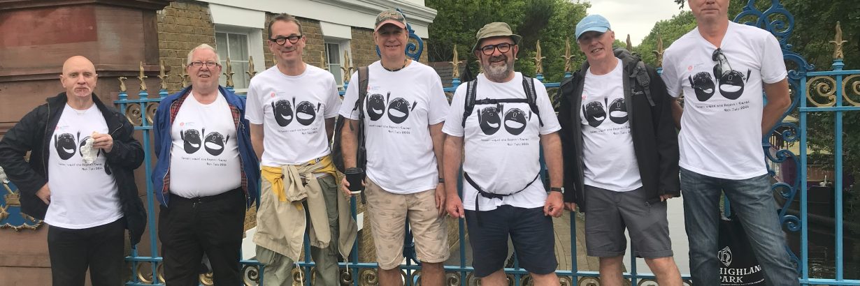 Group poses on a canal bridge. All wearing matching white t-shirts with the Headway logo.