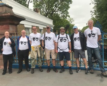 Group poses on a canal bridge. All wearing matching white t-shirts with the Headway logo.