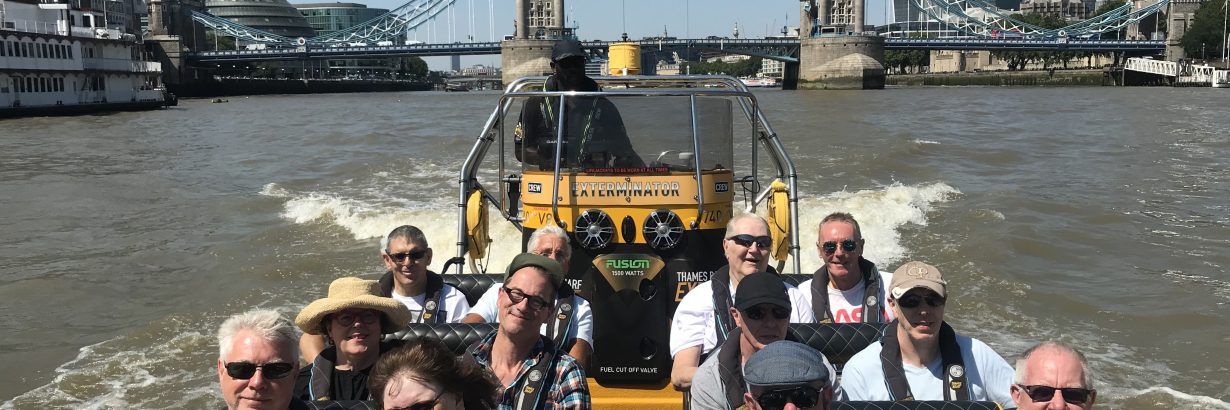 Group on speedboat on the River Thames. Tower Bridge and The Shard in background