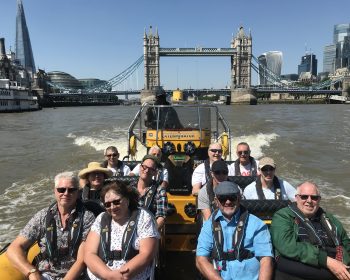 Group on speedboat on the River Thames. Tower Bridge and The Shard in background