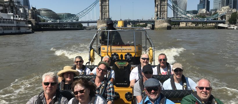 Group on speedboat on the River Thames. Tower Bridge and The Shard in background