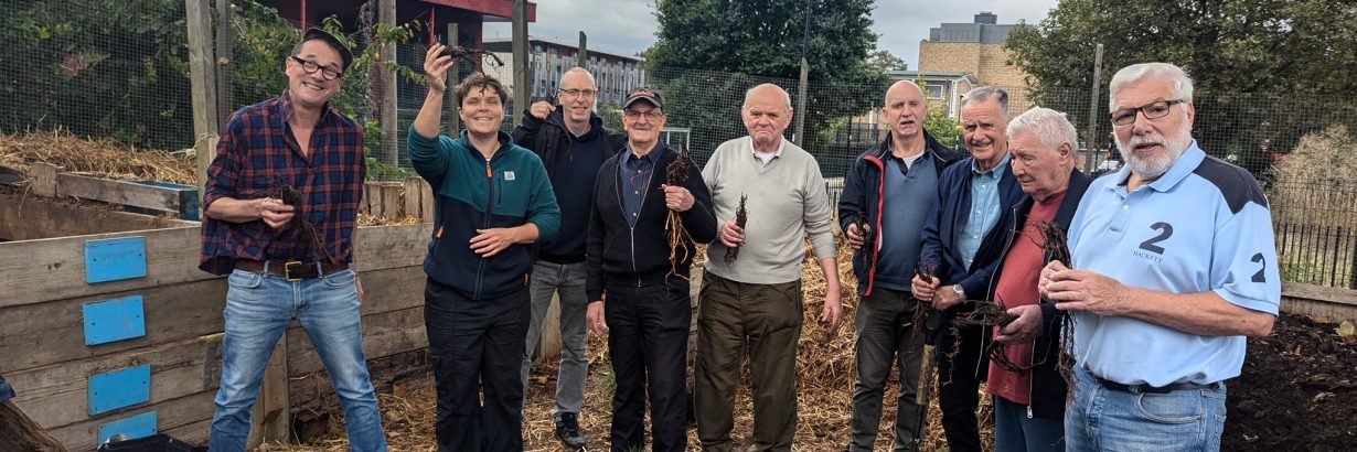 Group poses with gardening equipment and hop plants