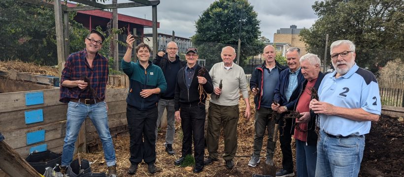 Group poses with gardening equipment and hop plants